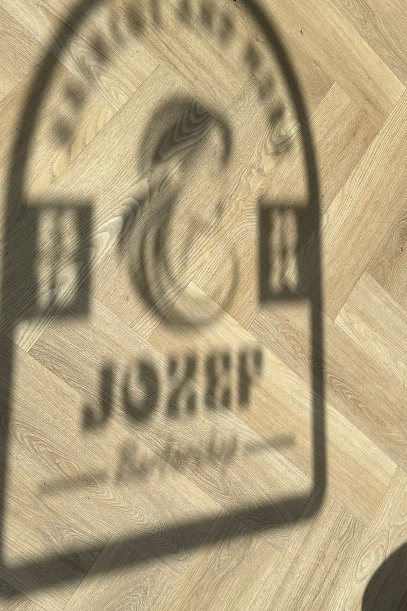 Het logo van Jozef barbershop, als lichtprojectie op de houten vloer